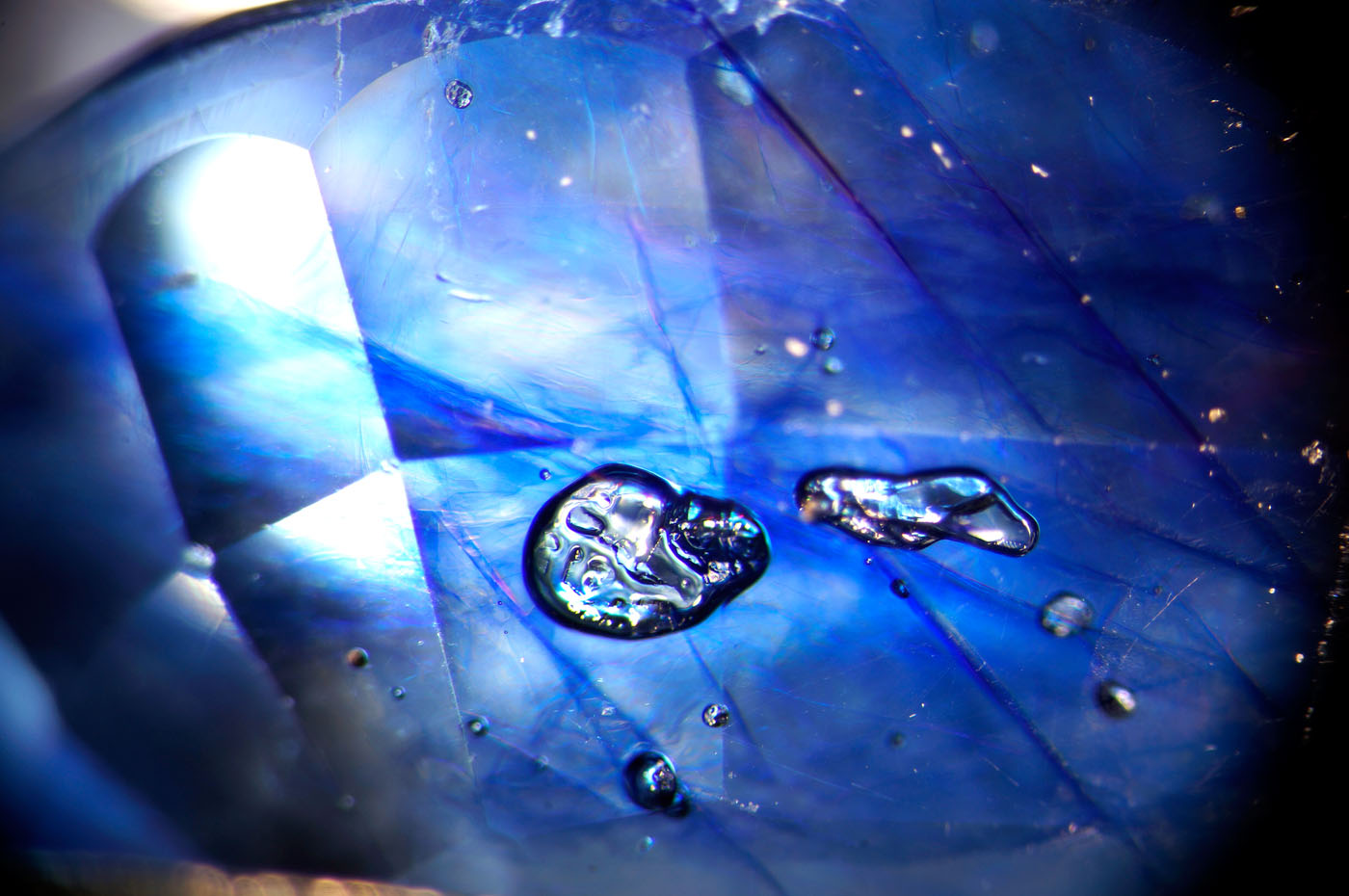 Figure 8. Flattened gas bubbles stand out in high relief in the glass filler of this cobalt-glass filled sapphire. Oblique fiber-optic illumination. (Photo: Wimon Manorotkul, Lotus Gemology).
