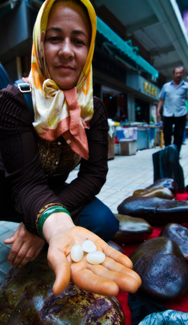 A Uighur woman showing what looks like Chinese nephrite in Guangzhou's Hualin Street jade market. From Lotus Gemology on jade and its imitations.