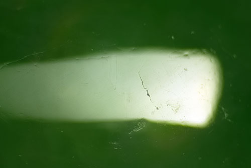 In contrast, the surface of an untreated jadeite shows only major cracks. Absent is the network of tiny microfractures created by bleaching
