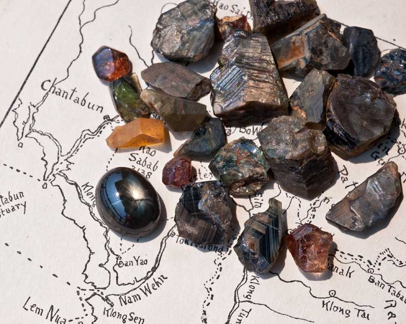 Rough gems from Khao Ploi Waen, along with one 12-rayed black star sapphire cabochon.