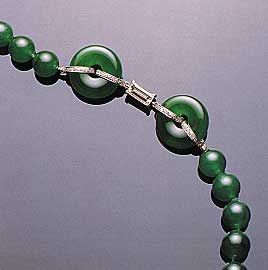 Figure 24. This necklace, which contains a total of 65 beads (7.8–9.8 mm in diameter) and two matching hoops, illustrates the optimum "vivid emerald green" color in fine jadeite. Note also the very fine "old mine" texture and translucency. Photo courtesy of and © Christie's Hong Kong and Tino Hammid.